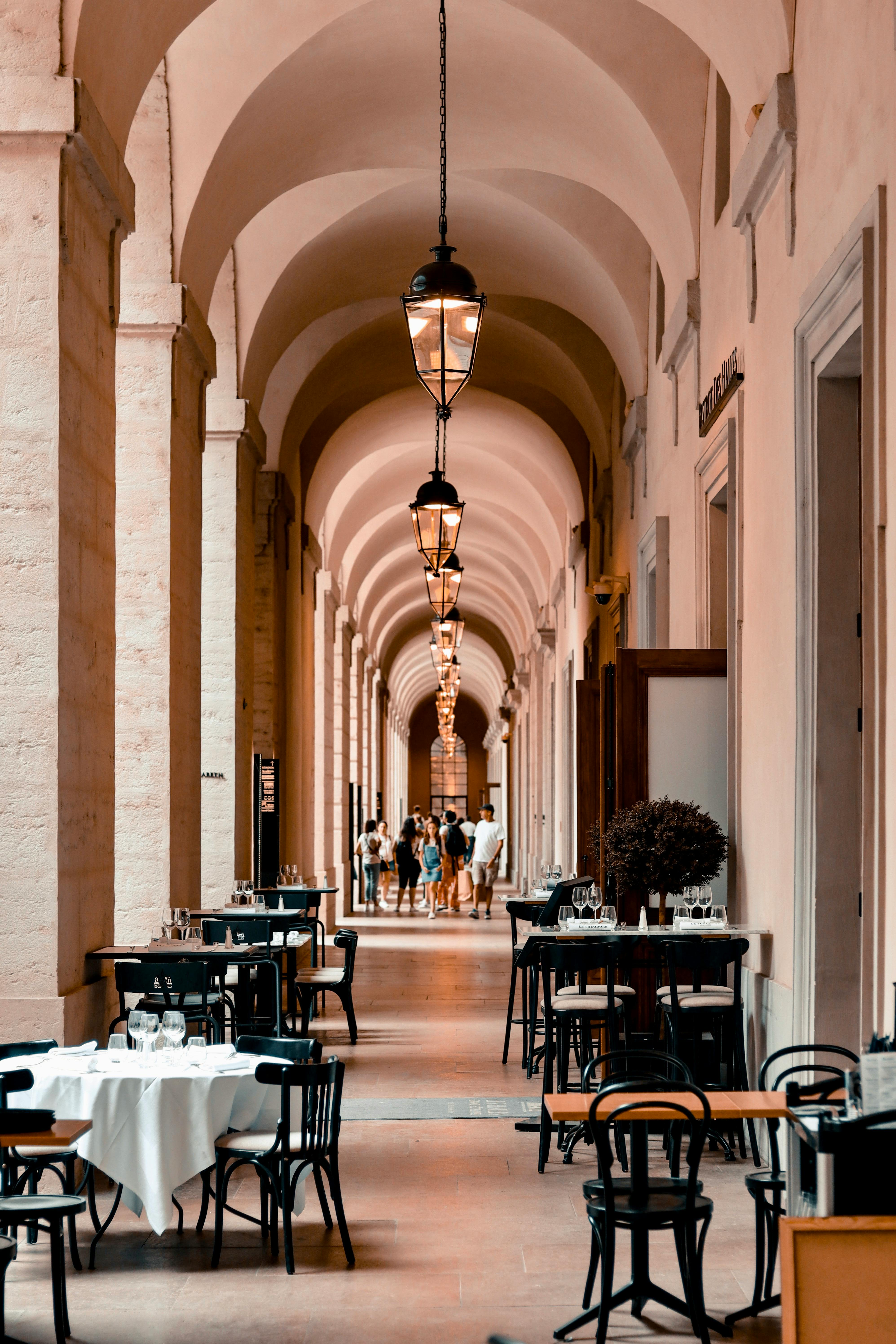 Photo by Assedrani Official : https://www.pexels.com/photo/people-and-restaurant-tables-in-a-long-vaulted-hallway-hotel-dieu-lyon-france-12606163/
