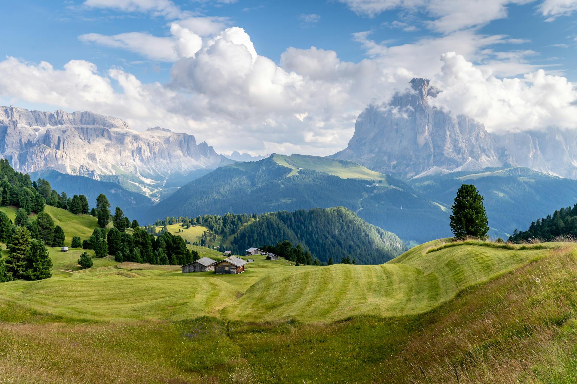 Green Grass Field Near Mountains Under White Clouds And Blue Sky. Photo by Chavdar Lungov